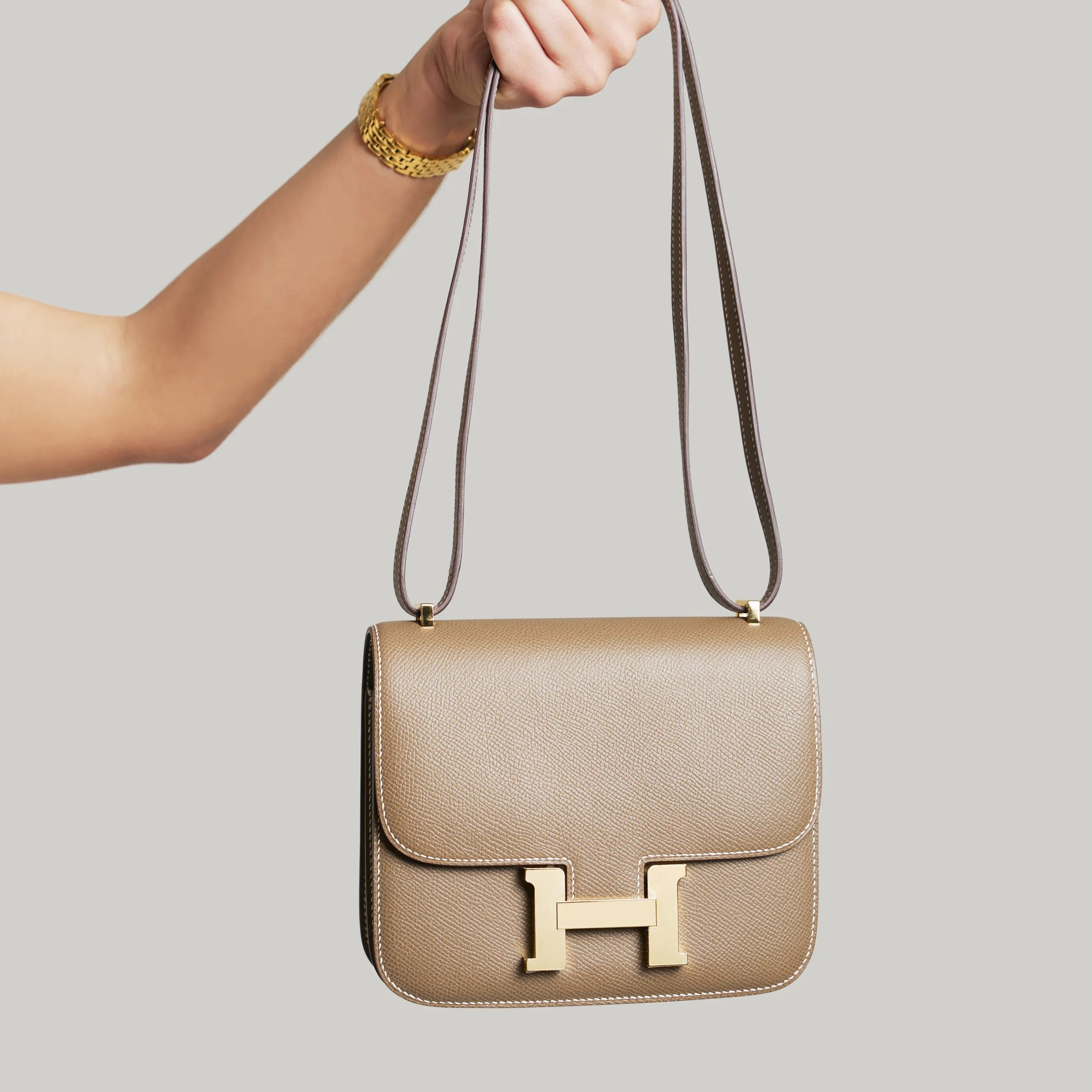 Hermès Constance bag in neutral leather held by hand