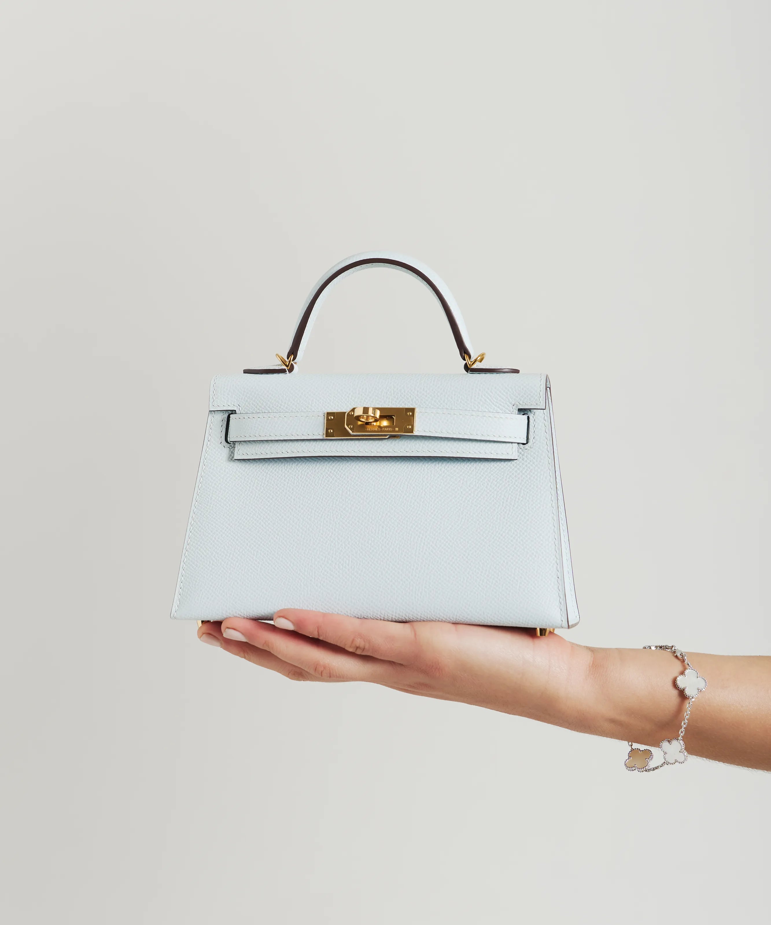 Bleu Brume Hermès Kelly mini bag with gold hardware held by hand