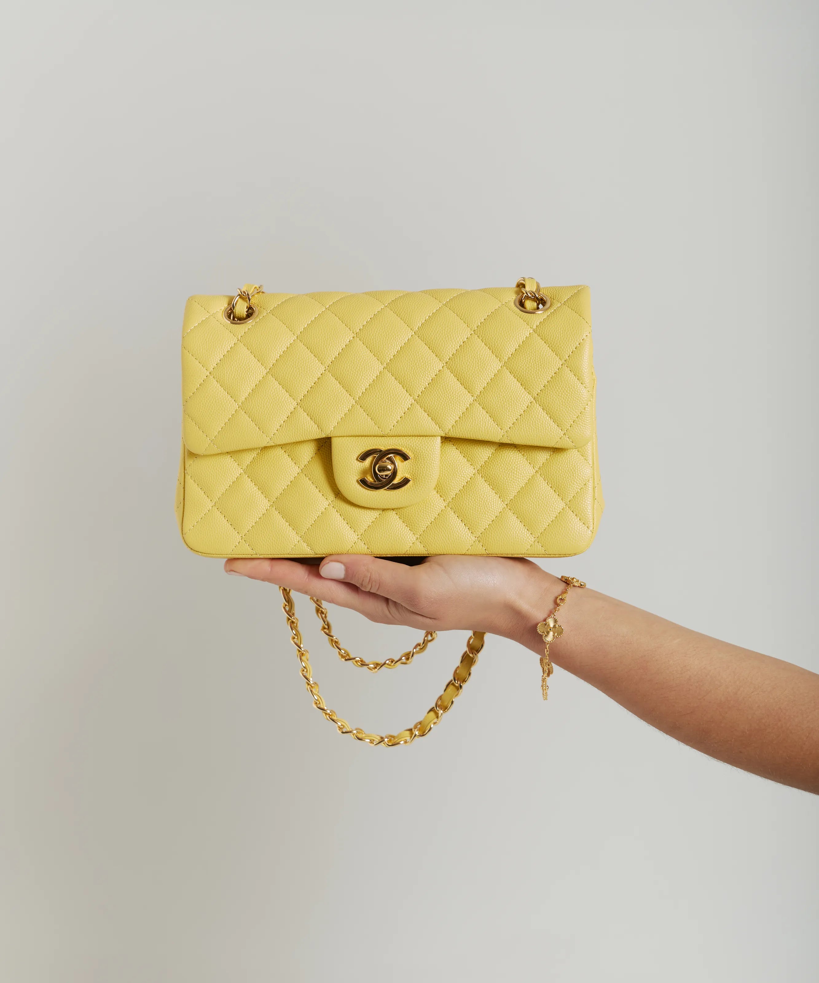 Yellow Chanel Double flap bag with gold-tone hardware held by hand