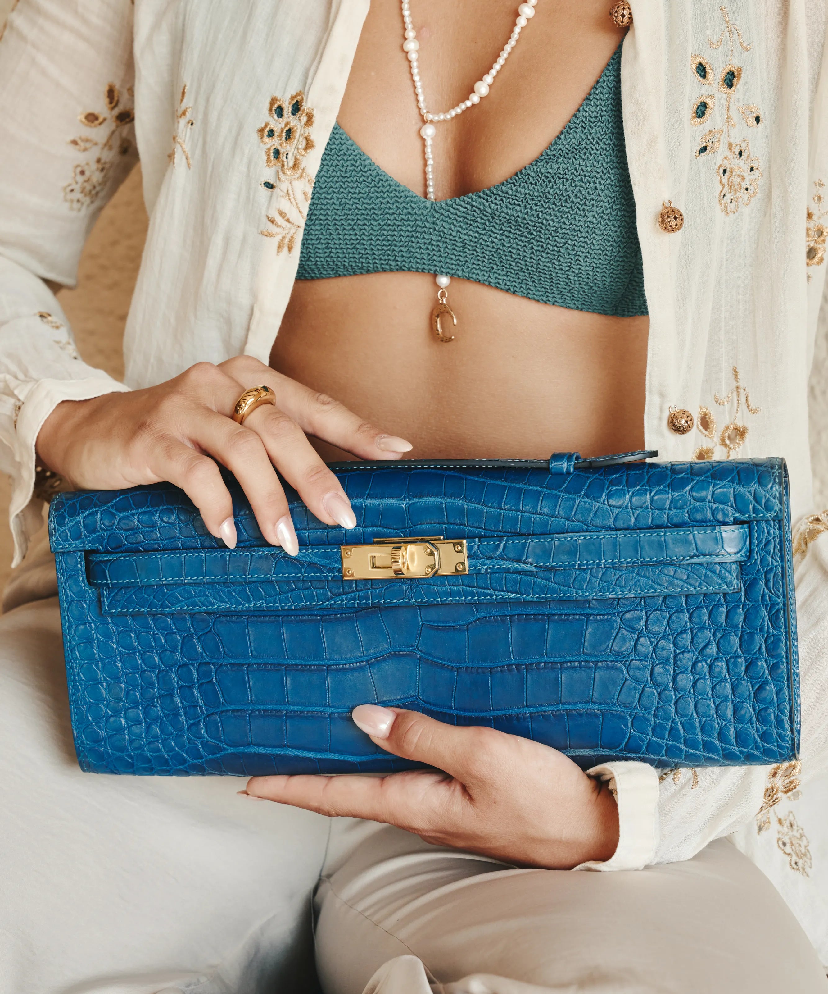 Hermès Bleu Kelly Cut Croc bag styled with summer jewelry and embroidered cover-up